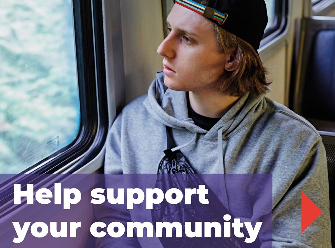 Young man on a train looking out of window. States help support your community.